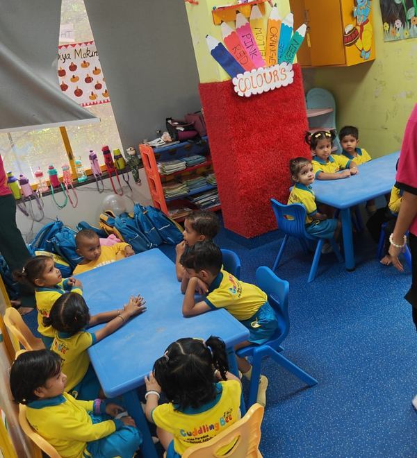 Children seated together beside a colours learning display