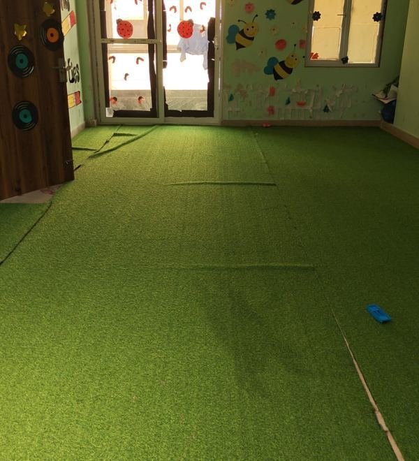 A soft-turf indoor play room decorated with hanging bee and fish cut-outs