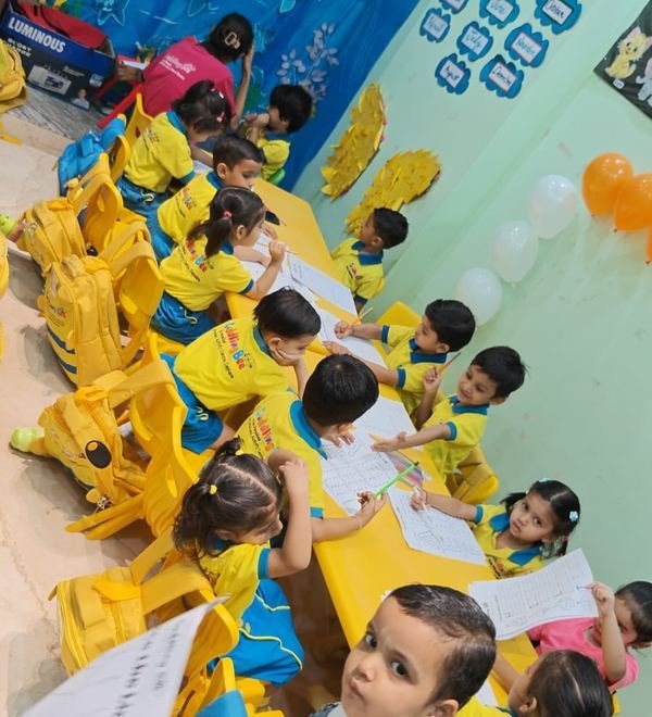 Children practising their writing on worksheets, decorated for Blue Colour Day